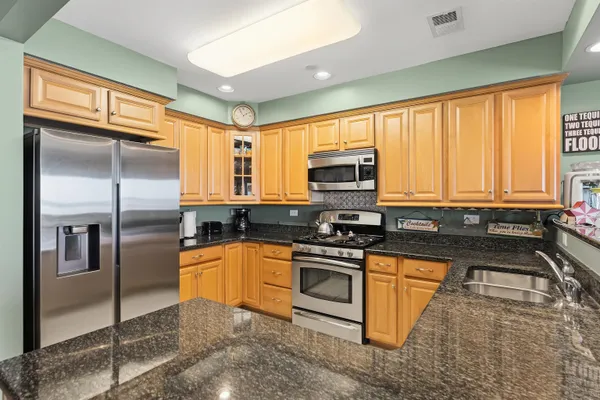 a kitchen with stainless steel appliances granite countertop a refrigerator a stove top oven a sink and dishwasher