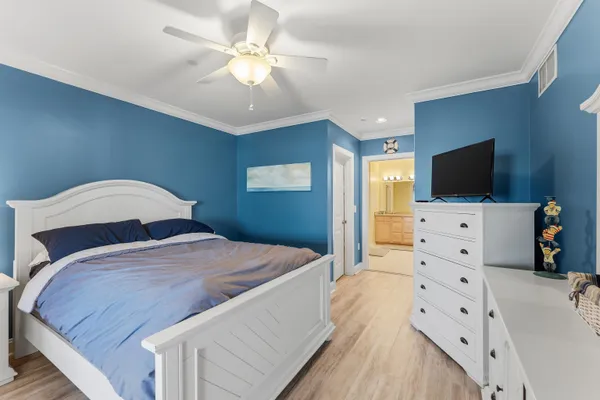 a spacious bedroom with a bed and a flat tv screen on dresser
