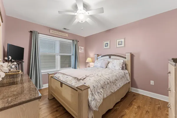 a spacious bedroom with a bed and a dresser with wooden floor