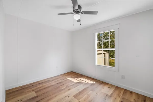 an empty room with a window and ceiling fan