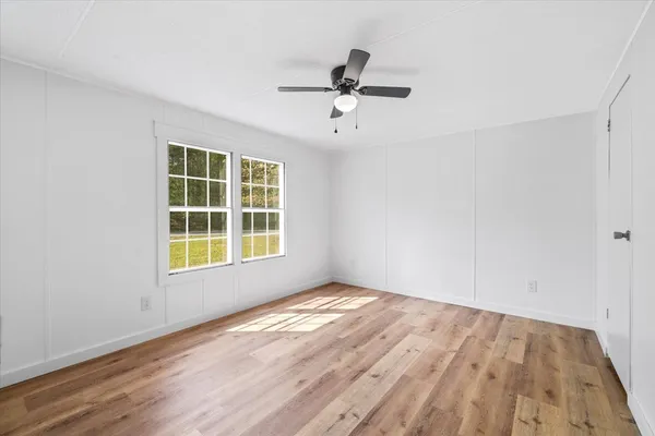 a view of an empty room with a window and wooden floor