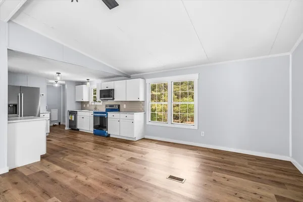 a view of a kitchen with wooden floor and electronic appliances