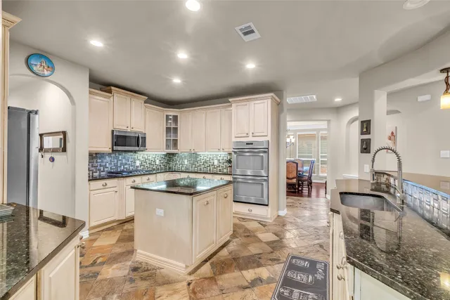 a kitchen with stainless steel appliances granite countertop a kitchen island a table and chairs