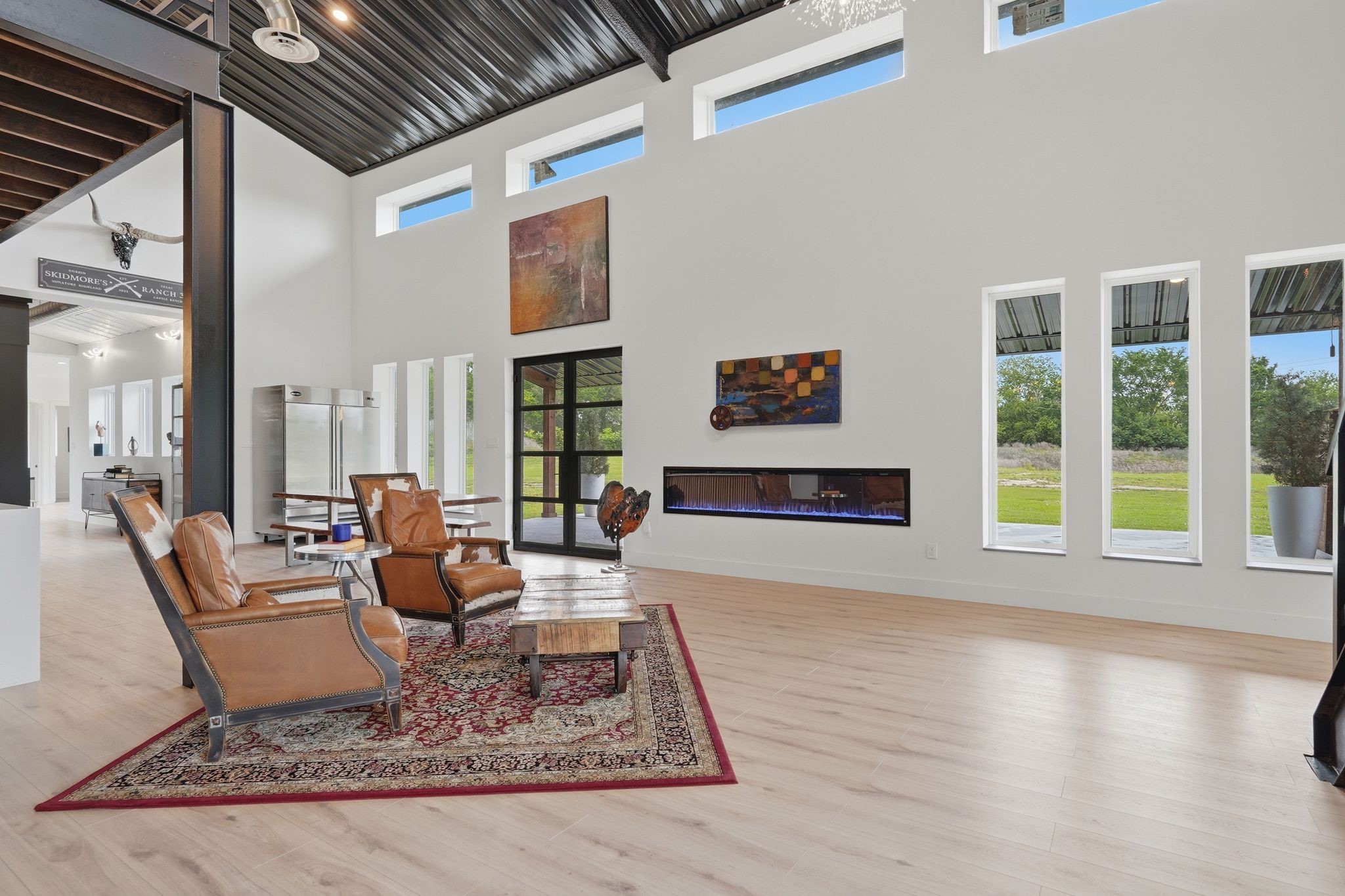 2743 Bobville Road Montgomery, TX 77316 - Photo 17 of 50 This spacious living area features high ceilings, large windows for natural light, modern decor, and a sleek electric fireplace. The open layout connects to a dining area, creating an inviting space perfect for entertaining.