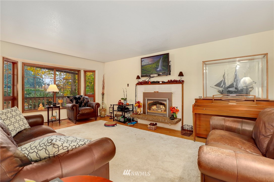 4313 212th Street Southeast Bothell, WA 98021 - Photo 5 of 40 a living room with furniture a fireplace and a floor to ceiling window