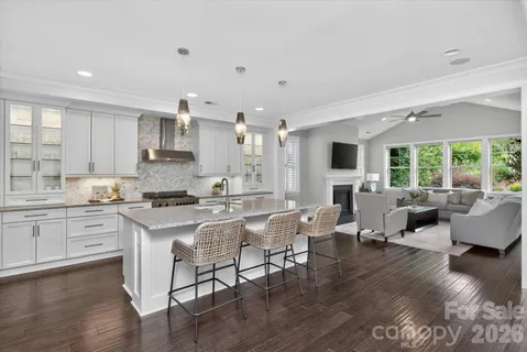 a kitchen with stainless steel appliances granite countertop a dining table chairs refrigerator microwave and cabinets