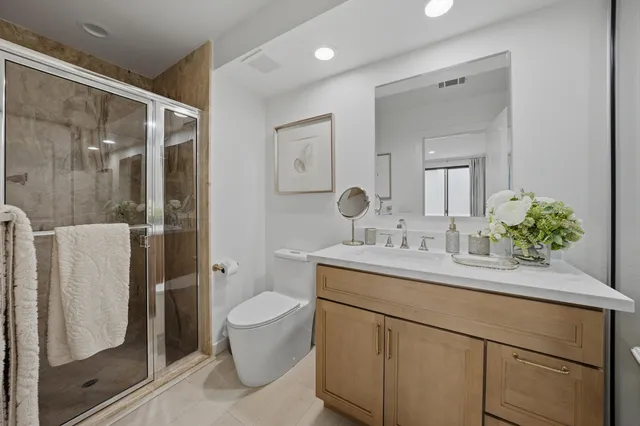 a bathroom with a granite countertop sink a toilet a mirror and shower