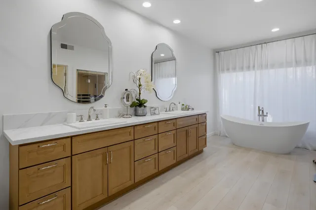 a spacious bathroom with a double vanity sink mirror and bathtub