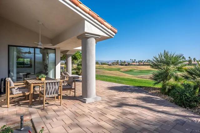 a patio with table and chairs and potted plants with wooden floor and fence