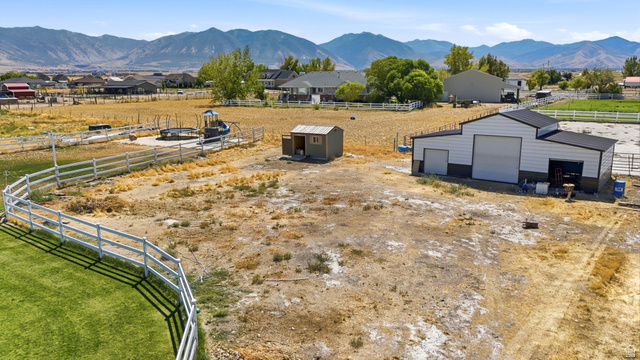 3644 Spiral Springs Road Tooele, UT 84074 - Photo 35 of 41 Expansive undeveloped land with a large outbuilding, a white fence, and distant mountain scenery