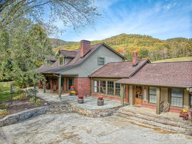 a view of a white house with large windows and a table and chairs under an umbrella