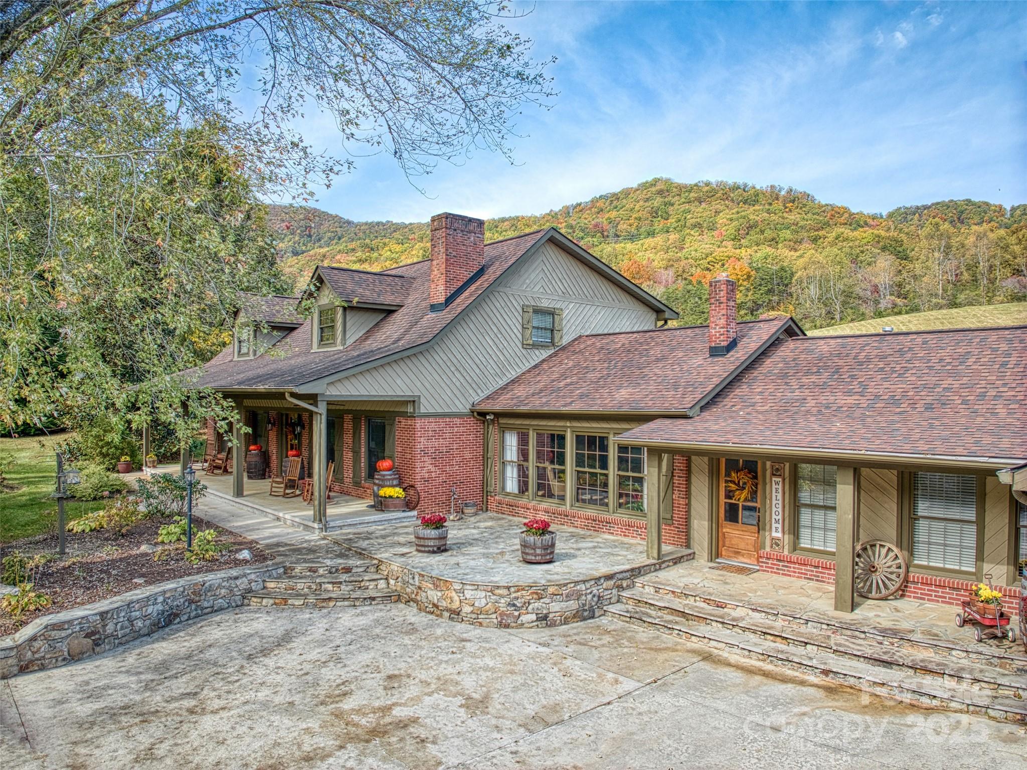 a view of a white house with large windows and a table and chairs under an umbrella