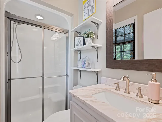 a bathroom with a granite countertop sink vanity mirror and shower