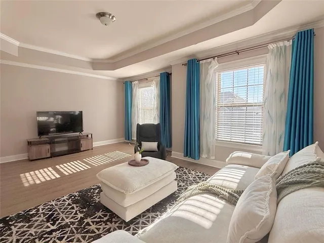 a bedroom with a bed a couch and a flat tv screen on a dresser