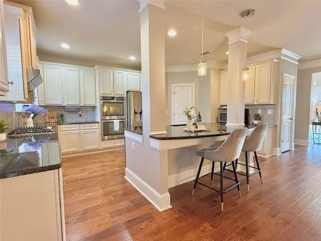 a large kitchen with granite countertop a large counter top a sink stainless steel appliances and cabinets