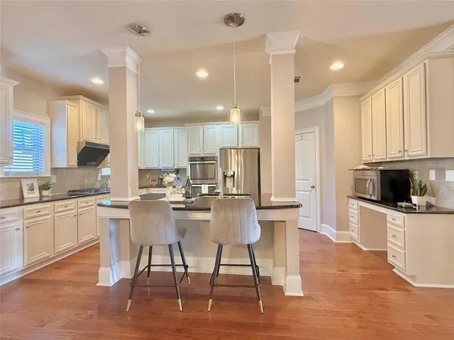 a kitchen with stainless steel appliances kitchen island granite countertop a stove top oven a sink a refrigerator and cabinets