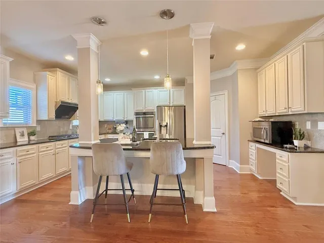 a kitchen with stainless steel appliances kitchen island granite countertop a stove top oven a sink a refrigerator and cabinets