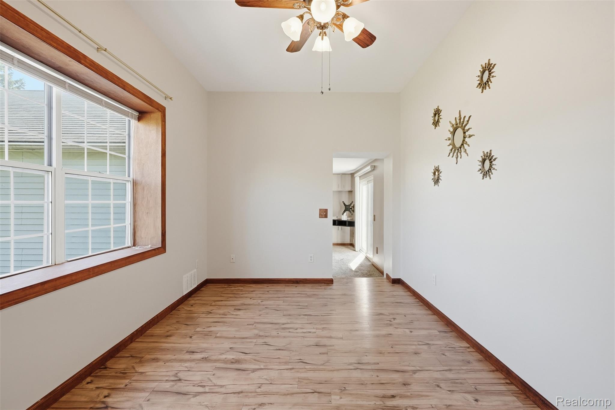 5634 Chicago Road Warren, MI 48092 - Photo 8 of 36 Spacious dining room featuring wood-finish flooring, a large window with white muntins, and a ceiling fan with integrated lighting