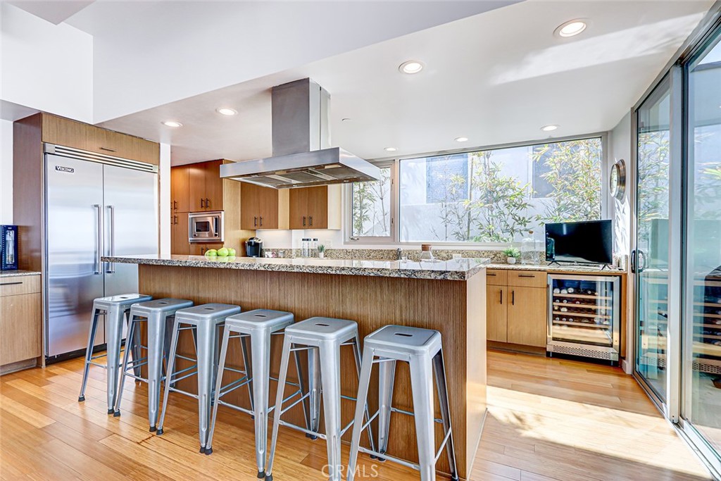 4321 Crest Drive Manhattan Beach, CA 90266 - Photo 15 of 37 a kitchen with stainless steel appliances granite countertop a stove top oven a refrigerator a dining table and chairs with wooden floor