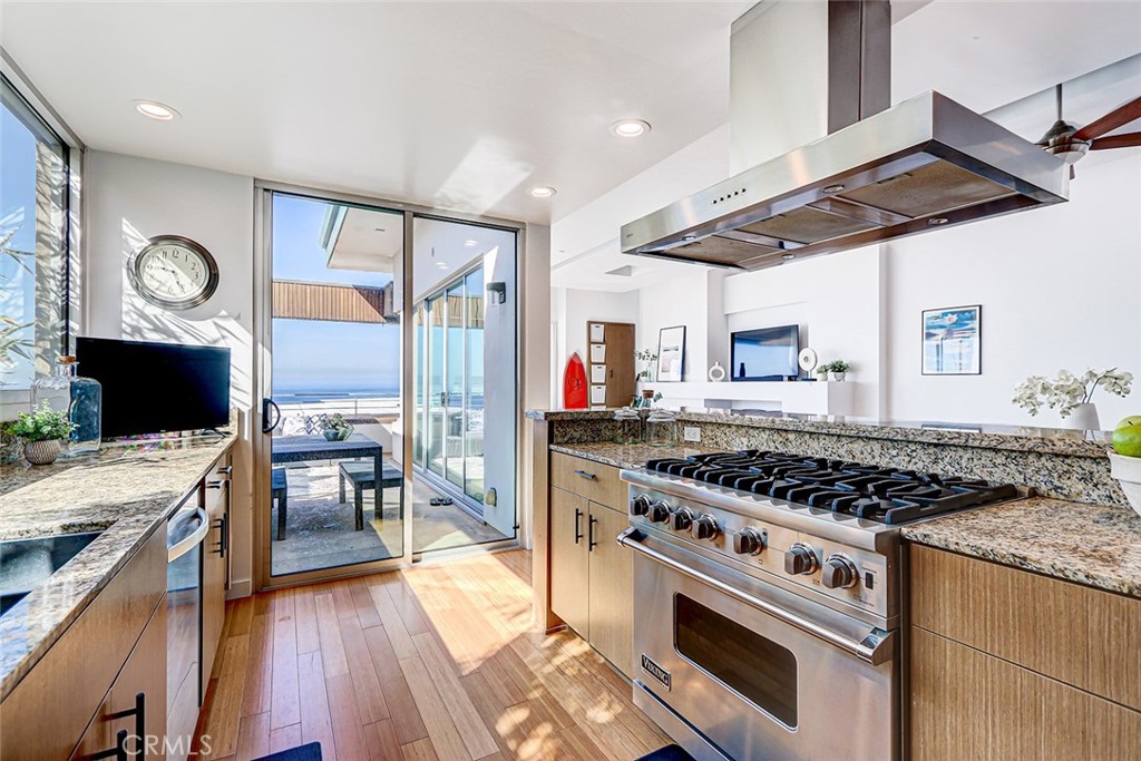 4321 Crest Drive Manhattan Beach, CA 90266 - Photo 16 of 37 a kitchen with stainless steel appliances granite countertop a stove top oven a sink dishwasher a dining table and chairs with wooden floor