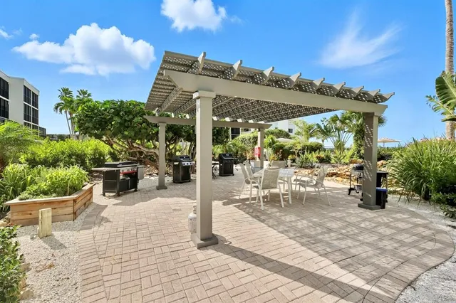 a patio with a table and chairs and potted plants