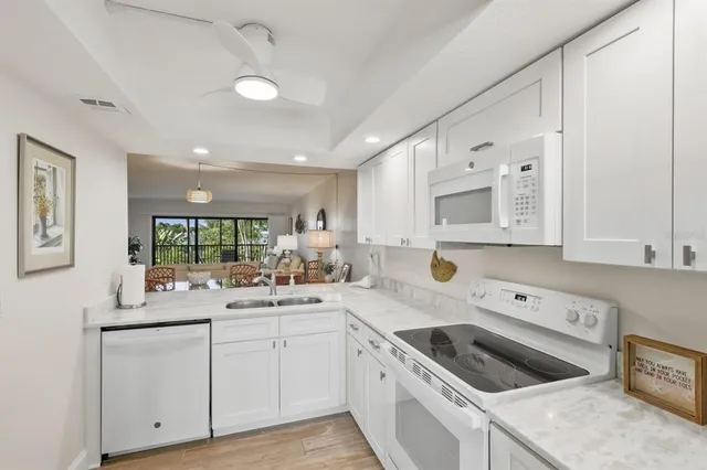 a kitchen with a sink dishwasher and white cabinets with wooden floor