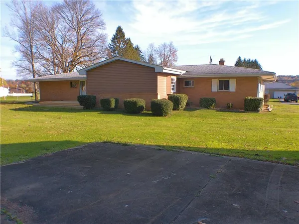 a view of a house with a yard and a large tree