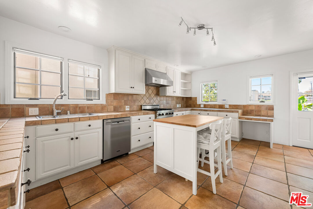 1849 Benecia Avenue Los Angeles, CA 90025 - Photo 7 of 59 a kitchen with a stove a sink and chairs