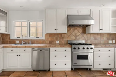 a kitchen with granite countertop white cabinets and white stove