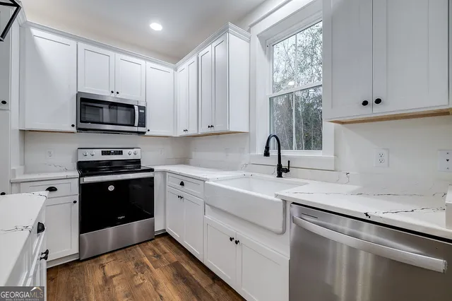 a kitchen with granite countertop a sink a stove and microwave with wooden cabinets