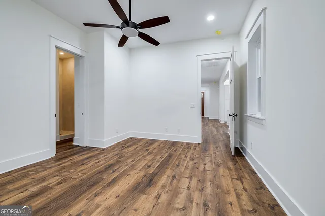 an empty room with wooden floor and a ceiling fan