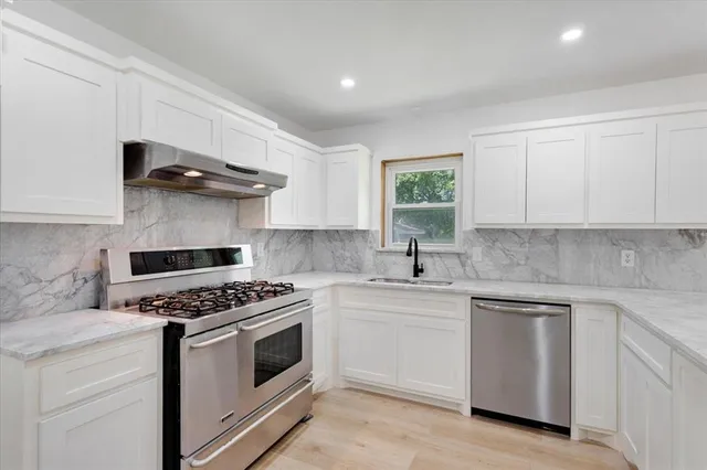 a kitchen with white cabinets and appliances
