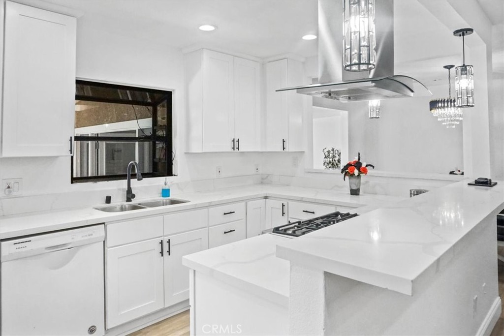 a kitchen with a sink dishwasher and white cabinets with wooden floor