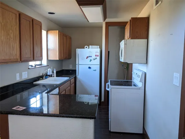 a kitchen with stainless steel appliances granite countertop a refrigerator a stove and a sink with wooden cabinets