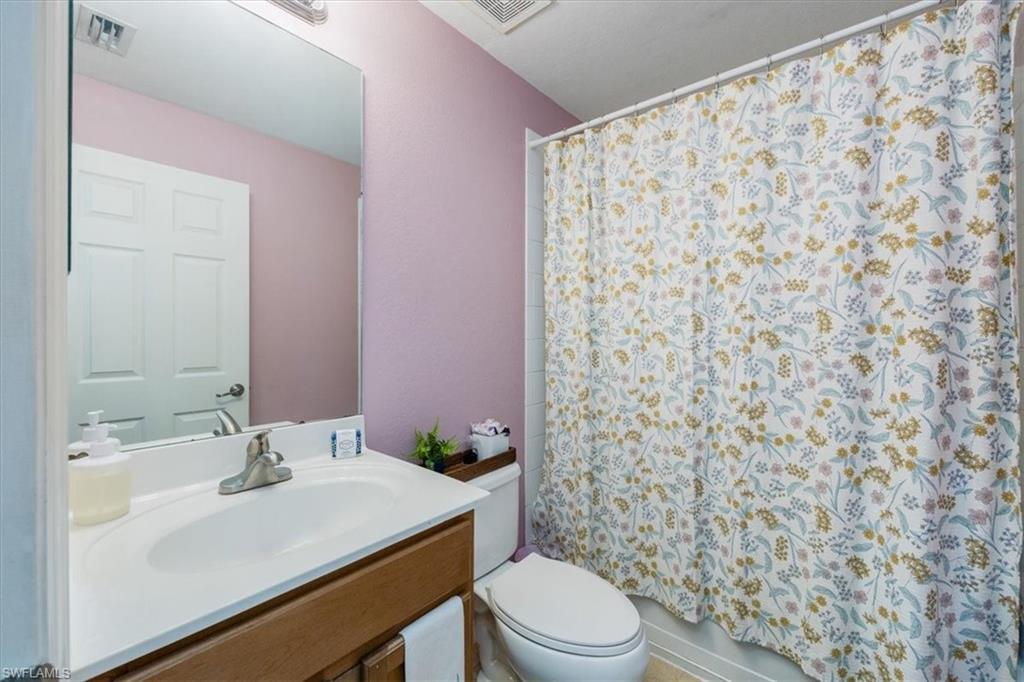 9072 Gervais Circle, Unit 307 Naples, FL 34120 - Photo 17 of 32 a bathroom with a sink a toilet and shower curtain
