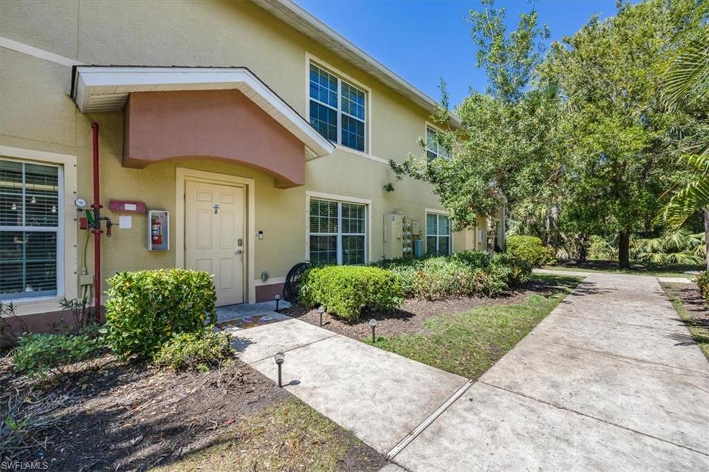 9072 Gervais Circle, Unit 307 Naples, FL 34120 - Photo 22 of 32 a view of a brick house with a yard plants and a large tree