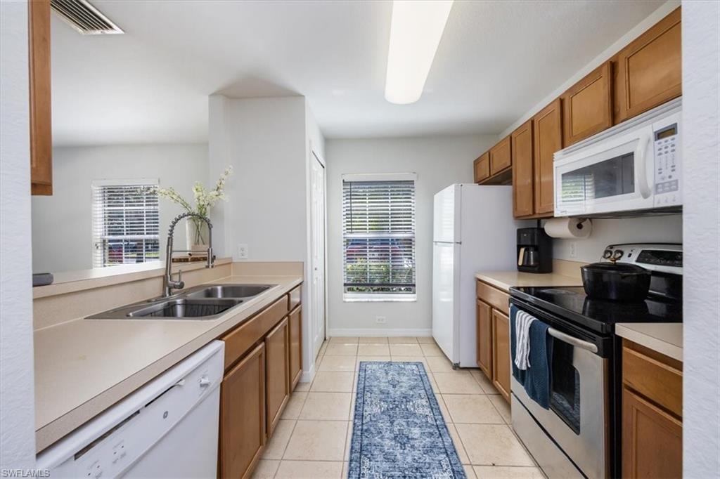 9072 Gervais Circle, Unit 307 Naples, FL 34120 - Photo 6 of 32 a kitchen with stainless steel appliances granite countertop a sink stove and refrigerator