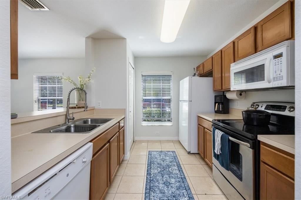 9072 Gervais Circle, Unit 307 Naples, FL 34120 - Photo 7 of 32 a kitchen with stainless steel appliances granite countertop a sink stove and refrigerator