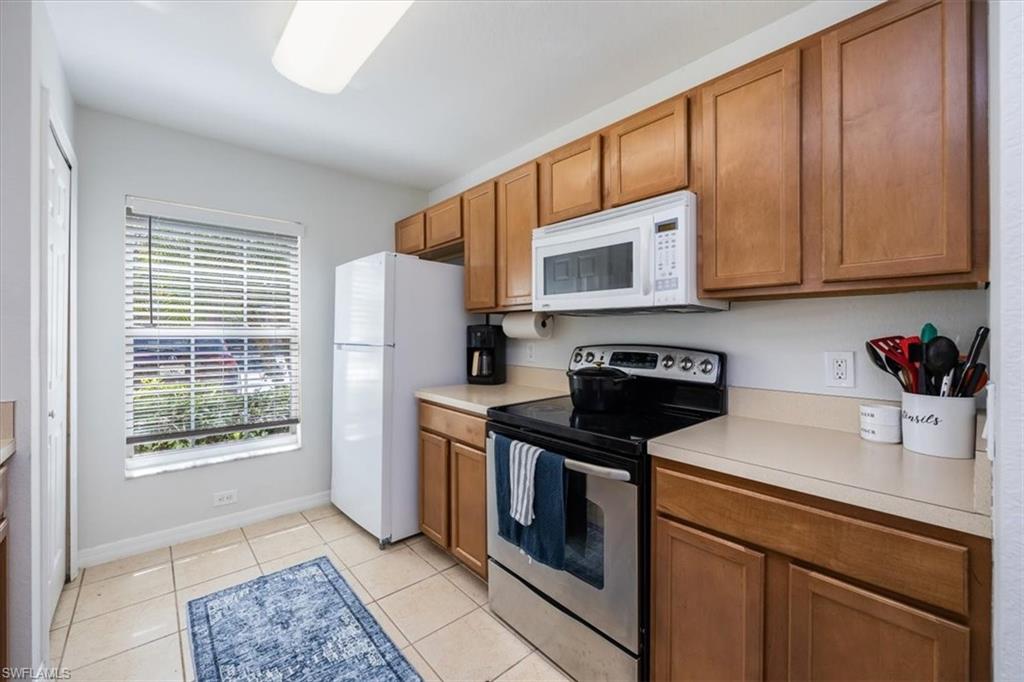 9072 Gervais Circle, Unit 307 Naples, FL 34120 - Photo 8 of 32 a kitchen with stainless steel appliances granite countertop a stove a sink dishwasher and a refrigerator with wooden cabinets