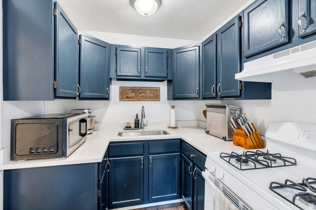 358 400 South Provo, UT 84601 - Photo 21 of 34 Kitchen with white gas range, blue cabinets, stainless steel microwave, and wood finished floors.