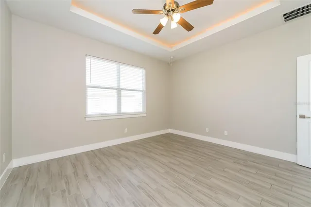an empty room with wooden floor fan and windows