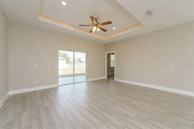 a view of an empty room with wooden floor and a ceiling fan