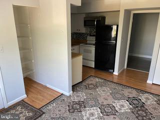 6907 Jones View Drive, Unit 3C Baltimore, MD 21209 - Photo 14 of 14 a view of a refrigerator in kitchen and an empty room in wooden floor