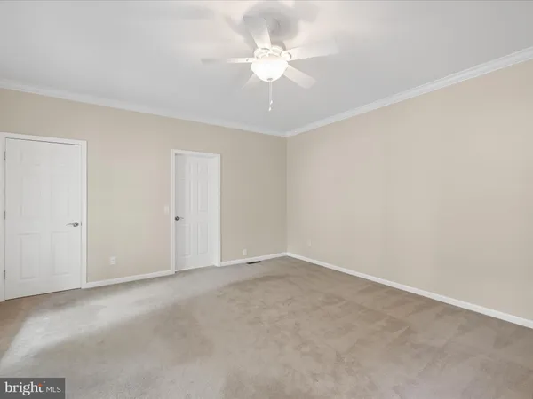 a view of an empty room with chandelier fan and kitchen view