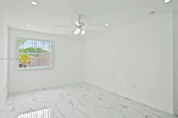 an empty room with a ceiling fan and windows