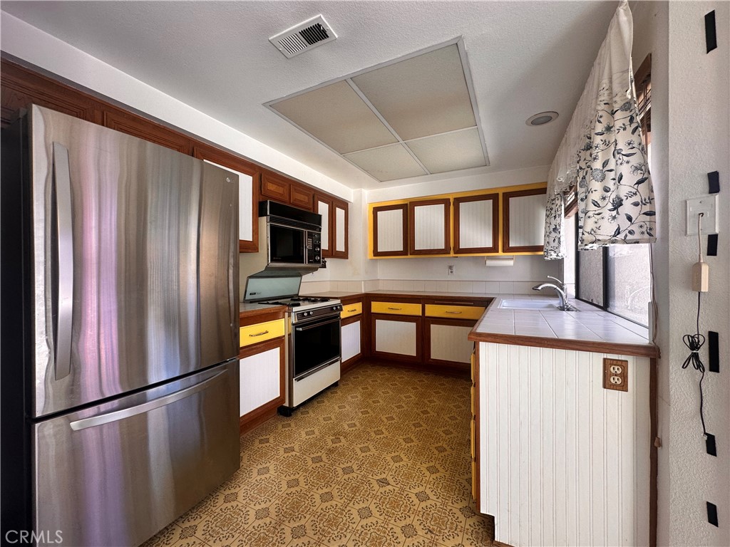 7 Wilderness Place Pomona, CA 91766 - Photo 12 of 26 a kitchen with stainless steel appliances granite countertop a refrigerator a stove a sink dishwasher a oven with white cabinets and wooden floor