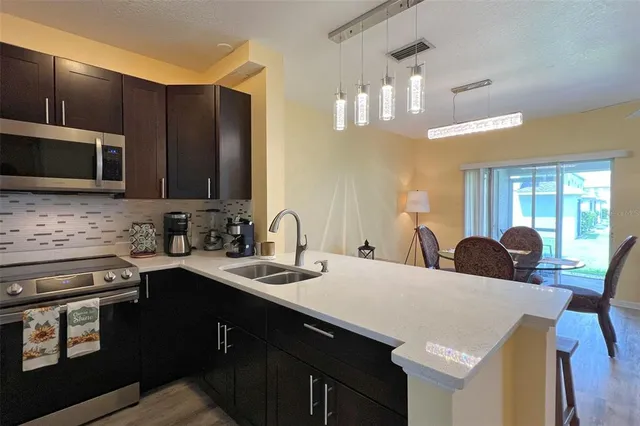 a kitchen with a stove a sink a microwave a dining table and chairs