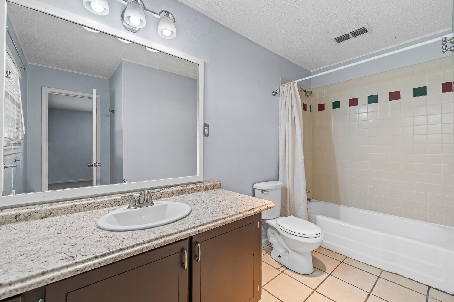 5204 7th Street Lubbock, TX 79416 - Photo 16 of 29 a bathroom with a granite countertop sink a toilet a mirror and shower