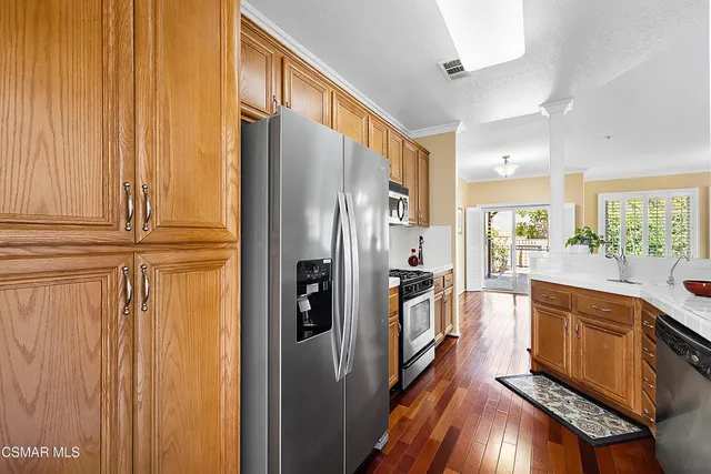 a kitchen with stainless steel appliances granite countertop a refrigerator a stove and a wooden cabinets