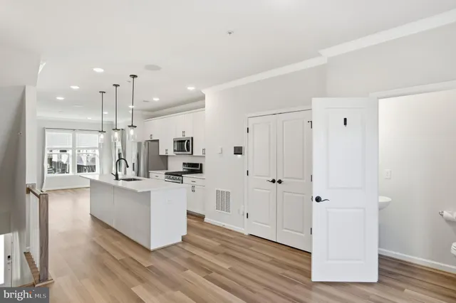 a large white kitchen with white cabinets and wooden floor